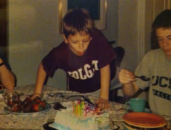 An old photograph of myself at maybe 6 years-old, climbing up on a dining room table with a funny look on my face.